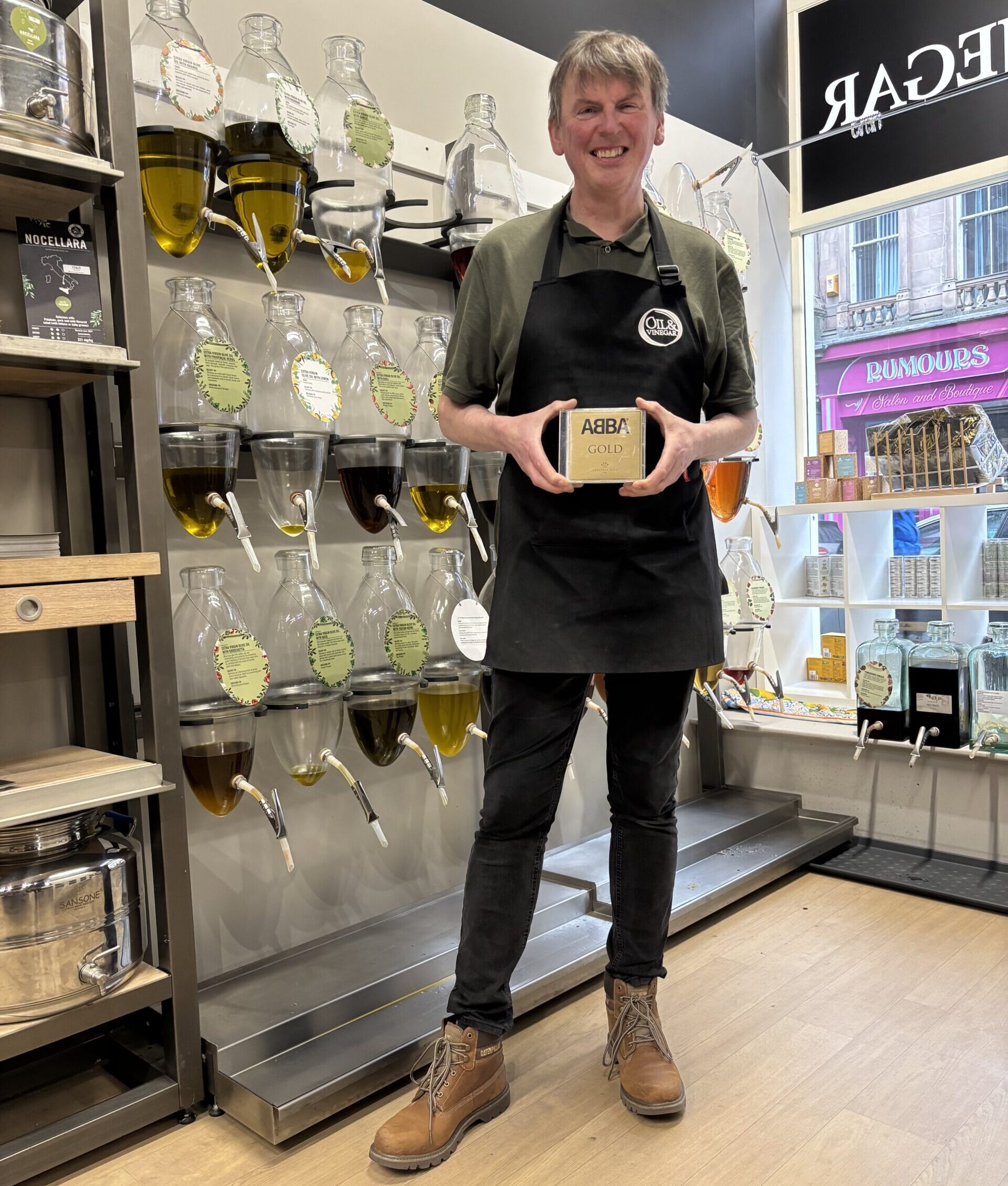 The Little Picture exhibition at Oil & Vinegar Inverness, holding artwork displayed in a CD case